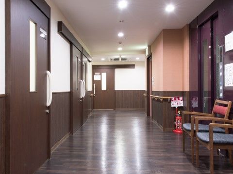 「御所南マリアヴィラ」廊下。廊下の天井と、天井から続く半分から上の壁は白。半分から下の壁と、床はブラウンの廊下。