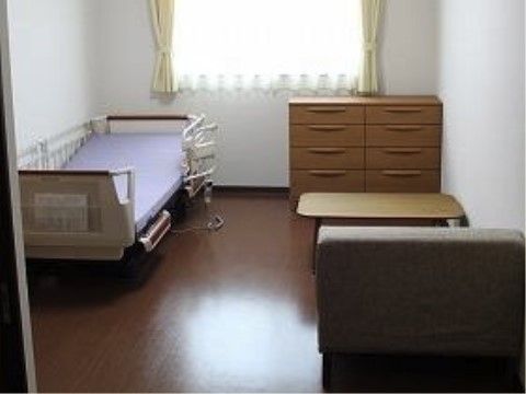 手元のリモコンでリクライニング可能なベッドを備えた居室