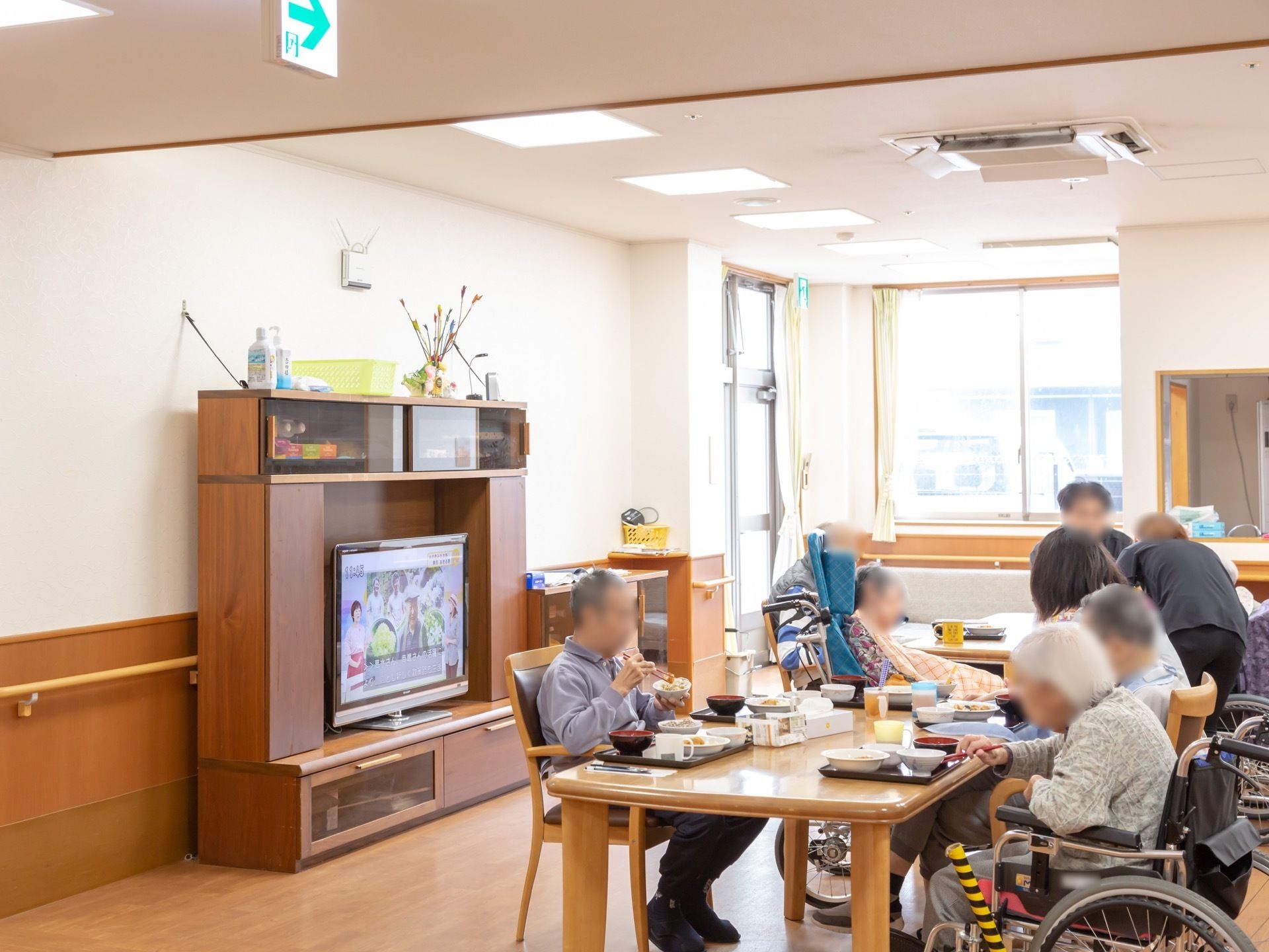 収納機能を備えたハイタイプのテレビボードがあり、大型テレビが設置されている。ボードは転倒防止ベルトで壁に固定されている。