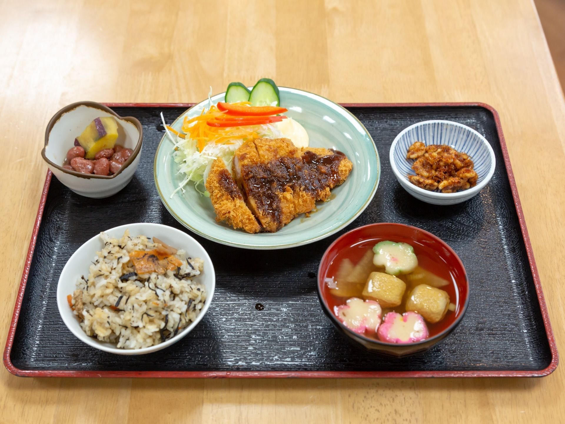 揚げ物をメインとした献立。付け合せの生野菜のほかに、副菜が２種、ひじきご飯に具たくさんのお吸い物が付いている。