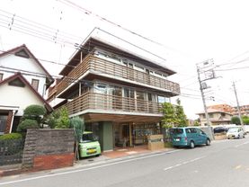 住宅地の道路に面した施設建物である。敷地の左隣は民家である。車をエントランス前に横付けして乗り降りする。