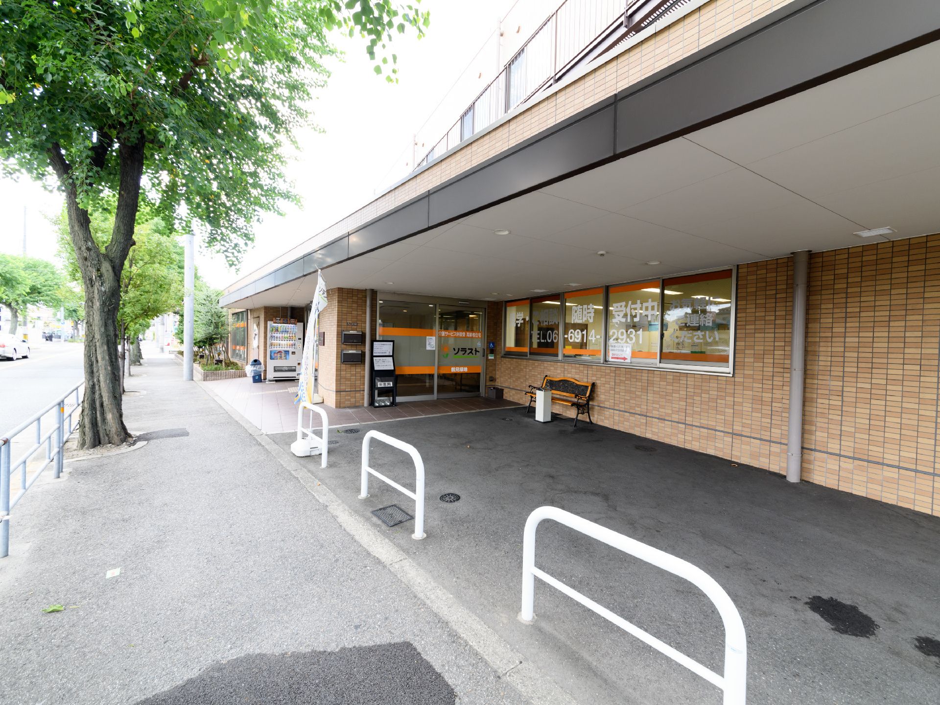施設外観の様子。窓には連絡先が大きく記載されている。道路に面したスペースには、喫煙コーナーが設置されている。