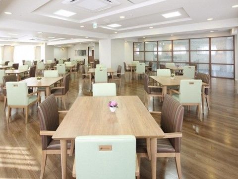リハビリホームグランダ甲子園弐番館の1F ダイニングルーム兼機能訓練室。大きなフロアにはたくさんのダイニングテーブルを設置。