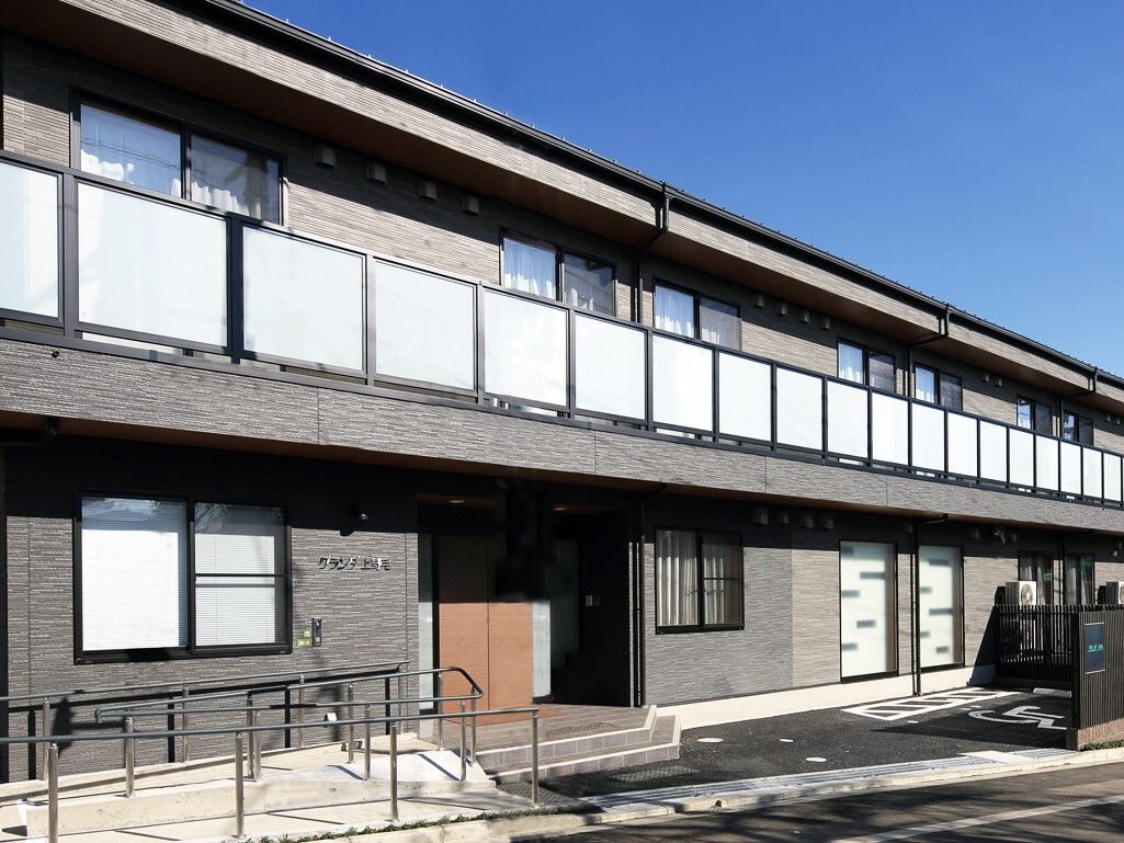 グレーの木目調で横に長い特徴のある、2階建ての施設の外観
