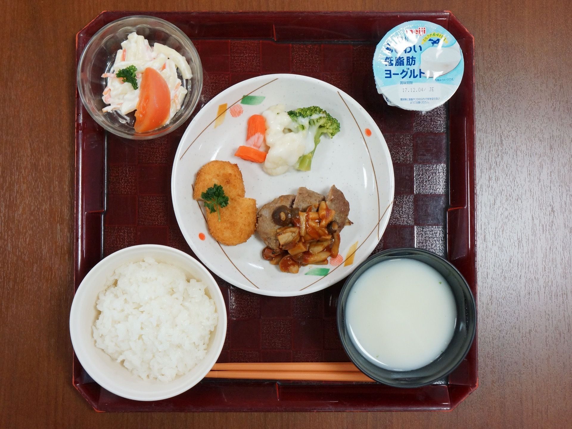 お盆に食事が載せられている。ご飯と汁物のほか、品数豊富なおかずやサラダ、デザートのヨーグルトがある。