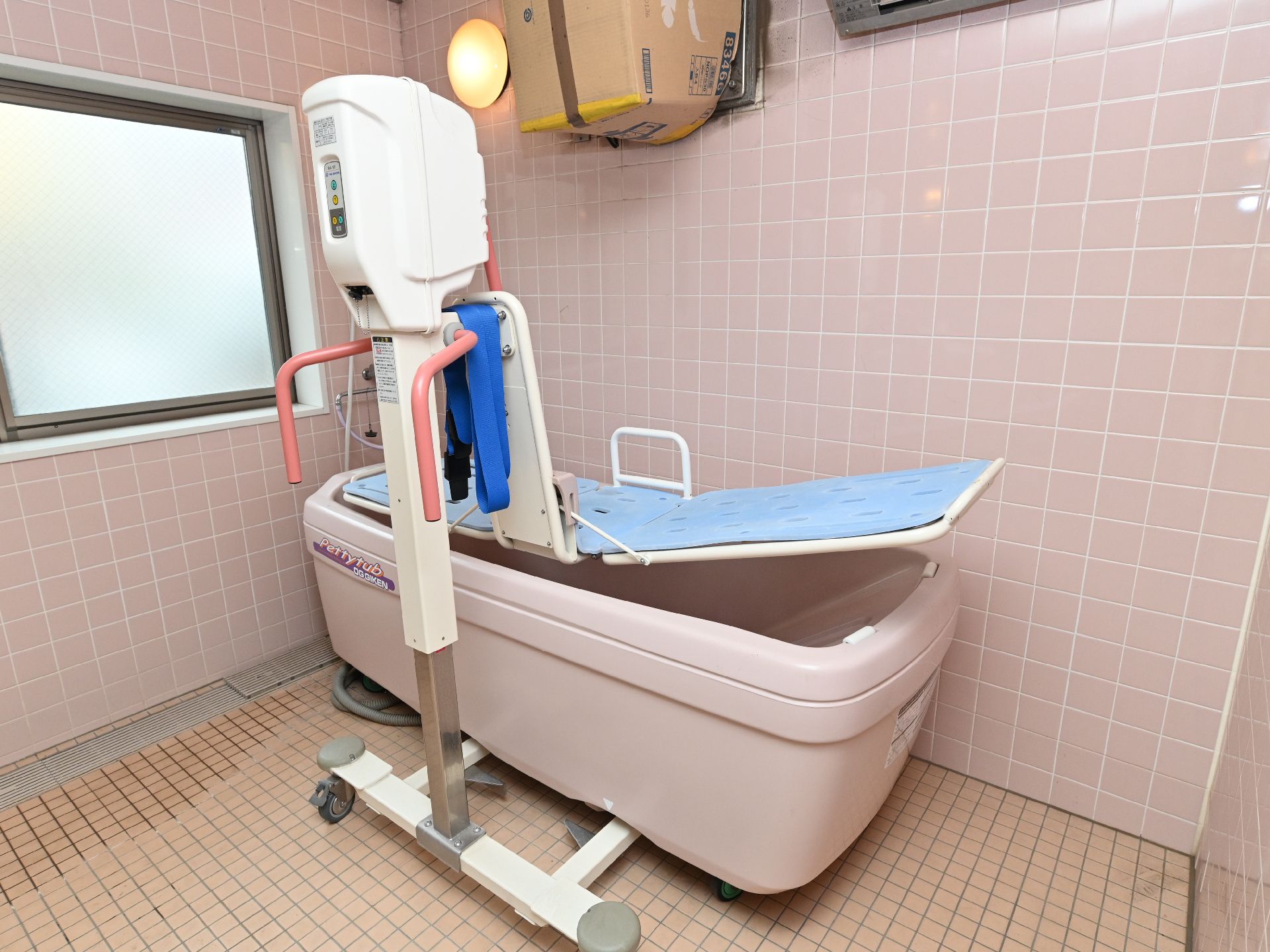 ピンクの浴槽とストレッチャーがついている特殊浴槽