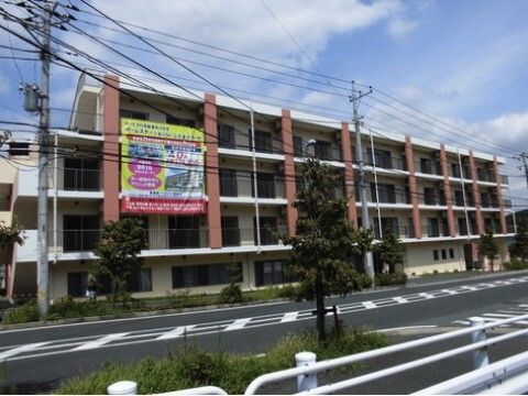 テーブルについている車椅子に乗った高齢者とスタッフの男性2人