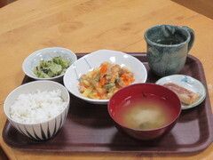 手前にご飯と味噌汁、奥におかずが3品とお茶が配置されているトレー