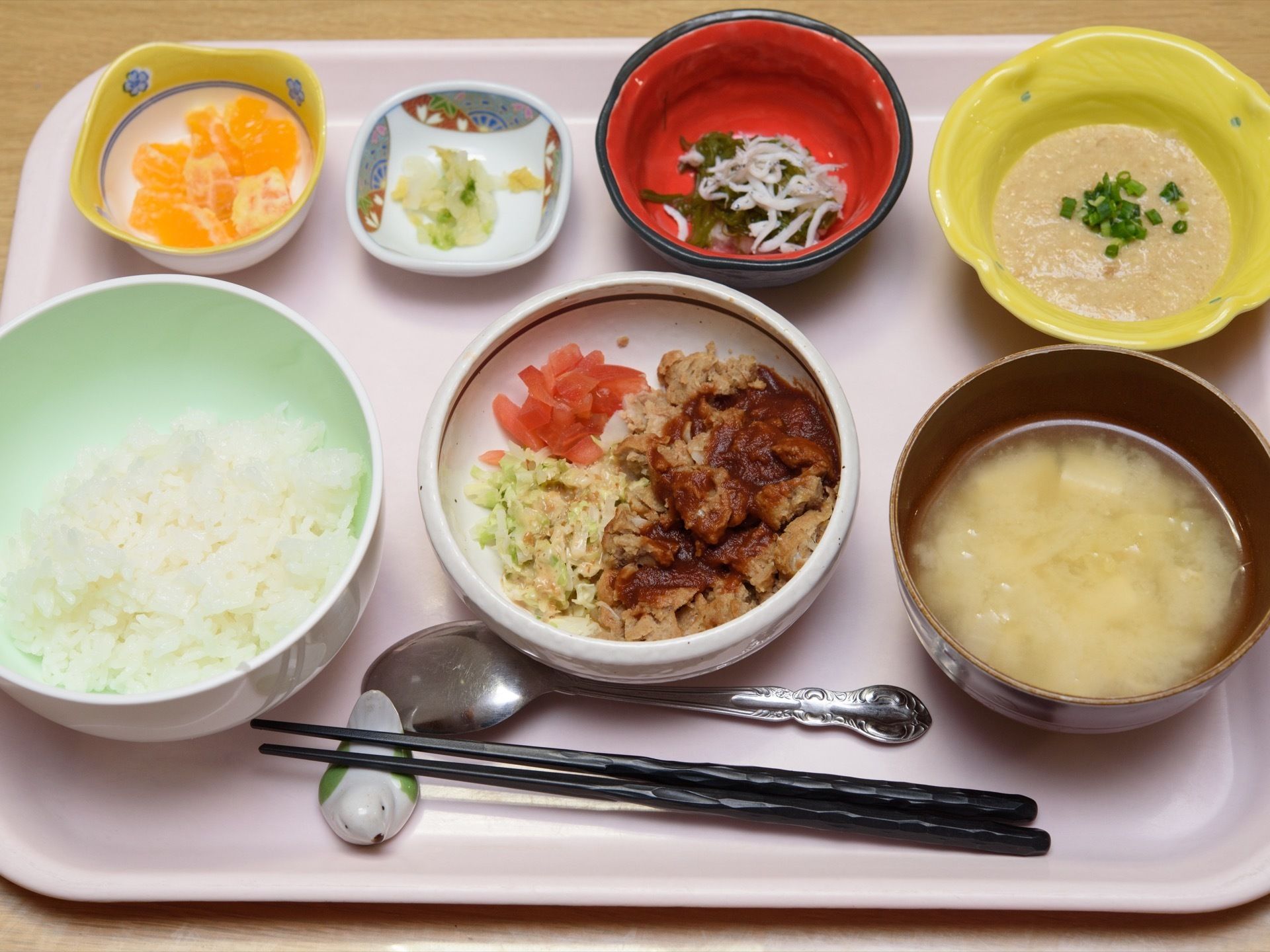 ご飯、おかず、味噌汁、小鉢、香の物、フルーツとお盆にいっぱいのせられた食事。品数が多くボリュームがある。