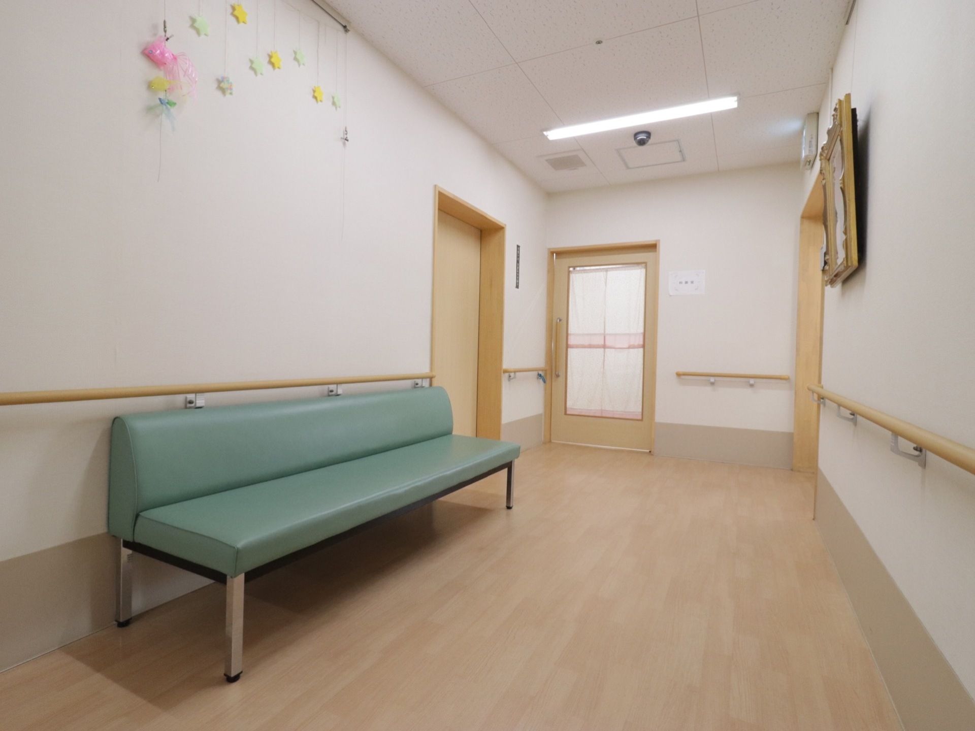 広さのある廊下。室内への扉が正面、左右に見られる。ベンチが置かれたり、壁に装飾がされたりしている。前面に手すりがついている。