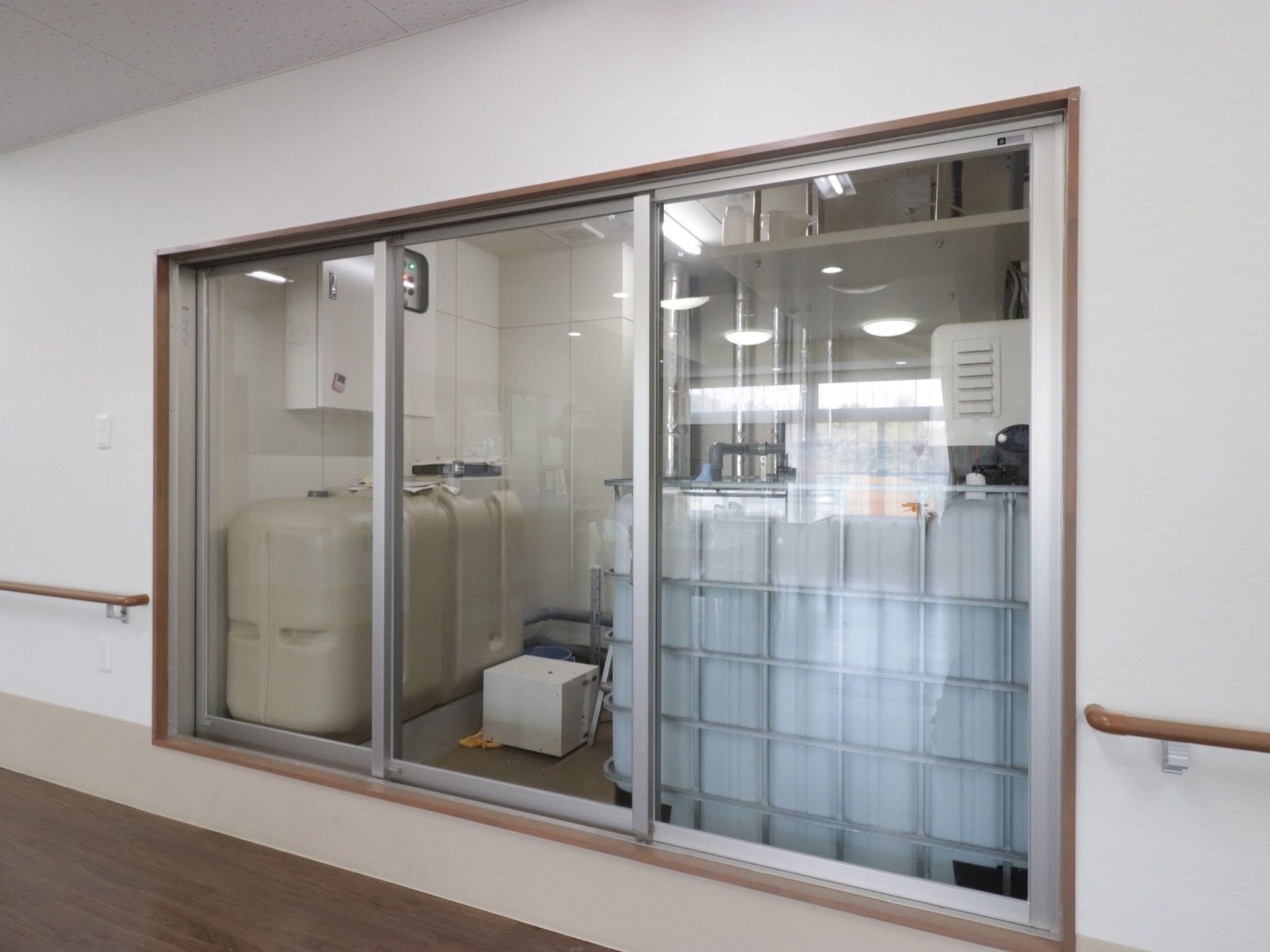 広々とした手すり付きの廊下から窓越しに設備室の内部を見ることができる。清潔感があり清掃が行き届いている。