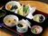 食事のメニューの一例である。膳の上に煮込みご飯、野菜の天婦羅、煮物、茶碗蒸し、漬け物、フルーツに汁物のお椀が置かれている。