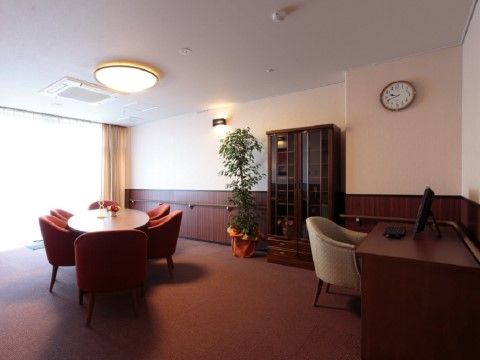 丸いテーブルの周りにソファが置かれ、パソコンが設けられたデスクも設置されている。周囲の壁には手すりが備えられている。