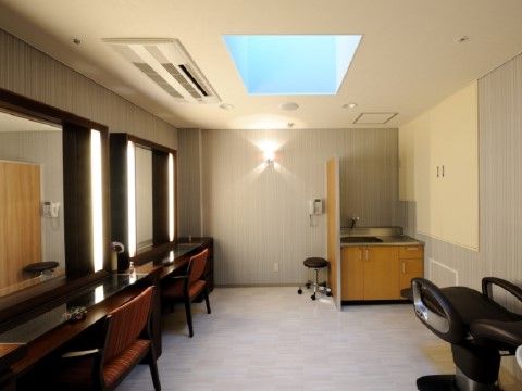 大きな鏡の前に手すり付きの椅子が置かれている。高い天井にはエアコン、証明設備が設置され、床には広いスペースが確保されている。