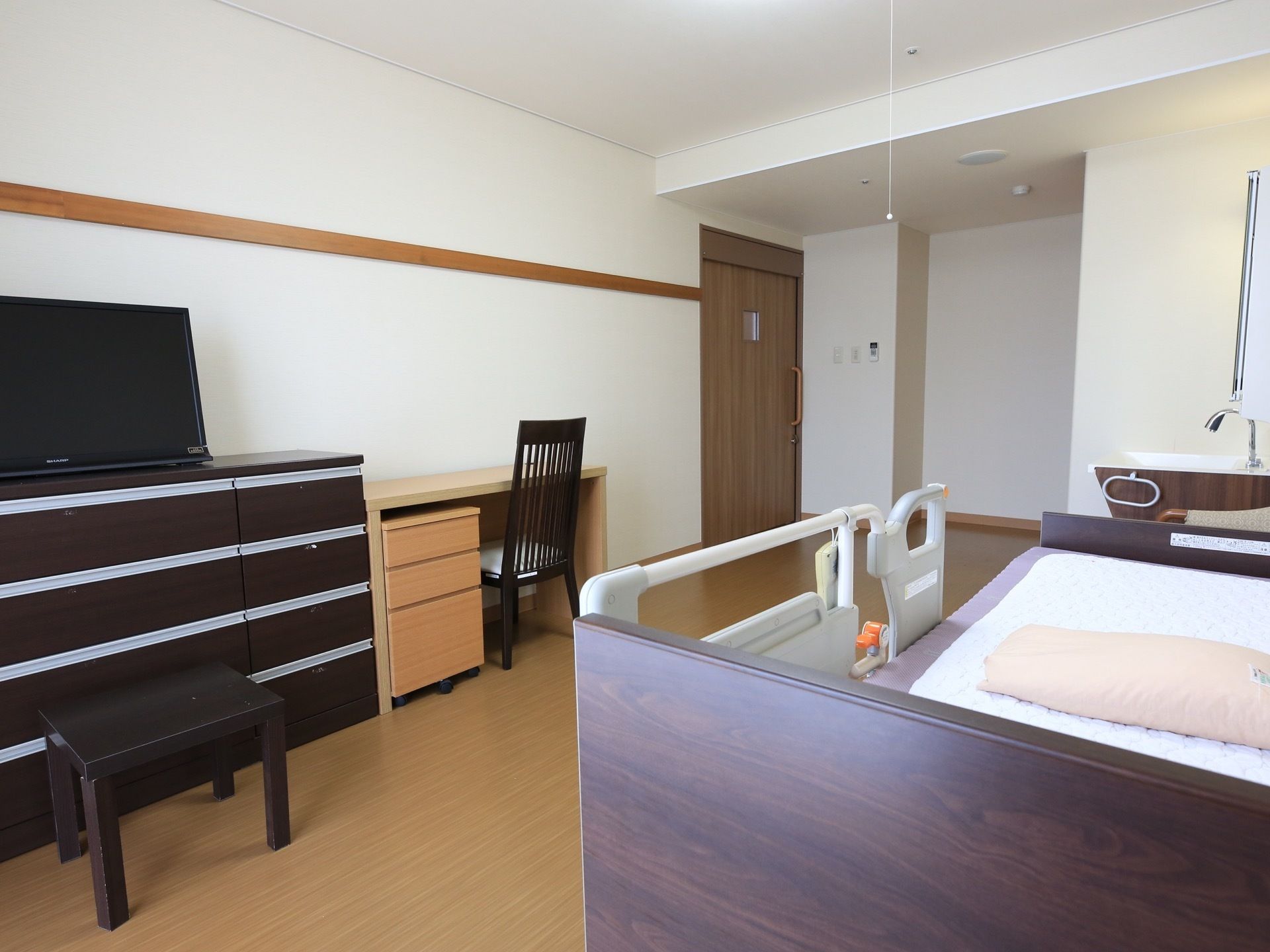 居室の壁際に、４段２列の引き出しがついた衣類収納タンスが設置されている。タンスの上にテレビが置かれている。