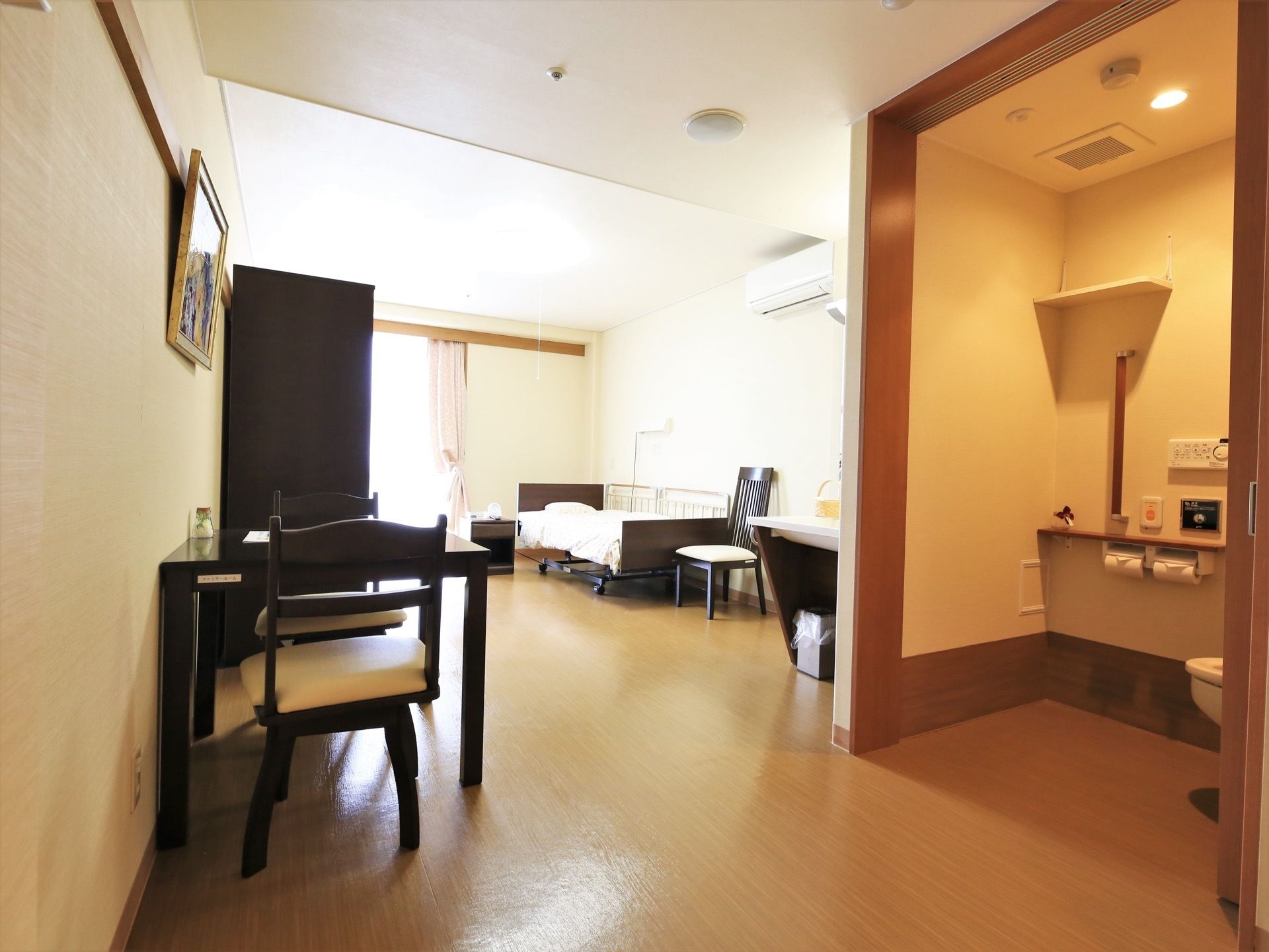 居室は、広いスペースが確保されている。入口を入ってすぐの所にトイレがある。水洗のボタンが壁に設置されている。