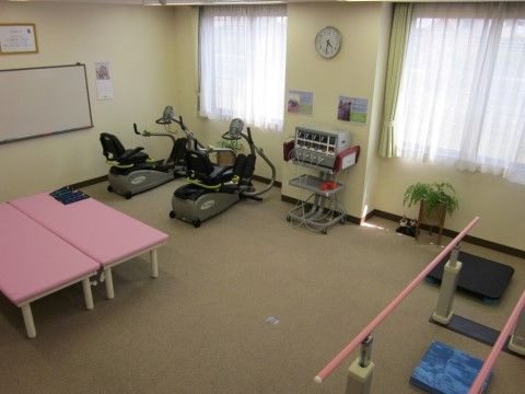 マッサージ用のベンチが２台、トレーニングバイクが２台と歩行訓練に使用する手すりがある。入居者様が機能訓練に使用する。