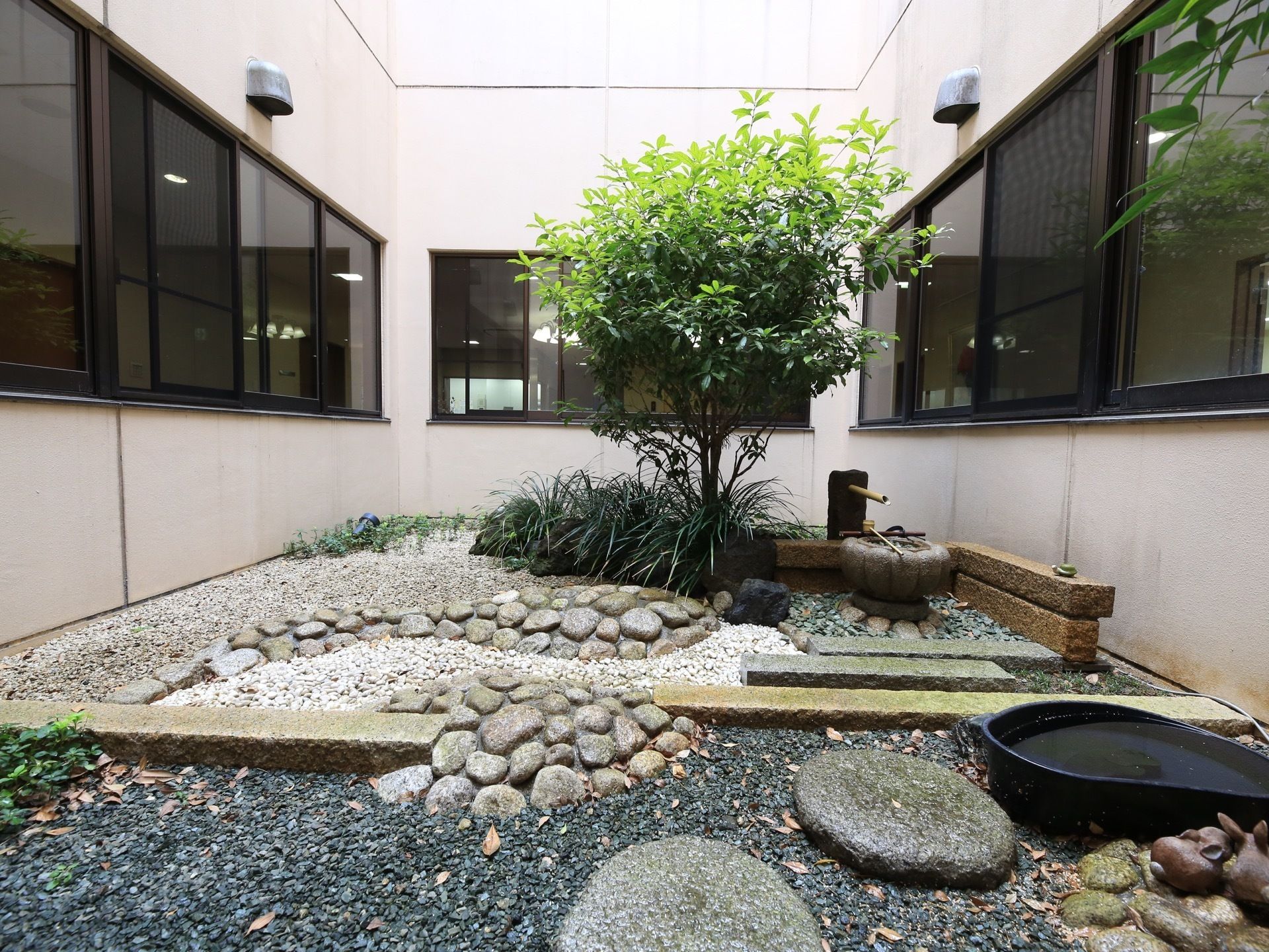 日本庭園風の中庭。廊下の窓越しに眺めることができるようになっている。丸い水の鉢があり、柄杓が置かれている。