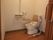 トイレは、大きな取っ手がついた引き戸の奥に設置されている。便器の周りには、手すりや背もたれが取り付けられている。
