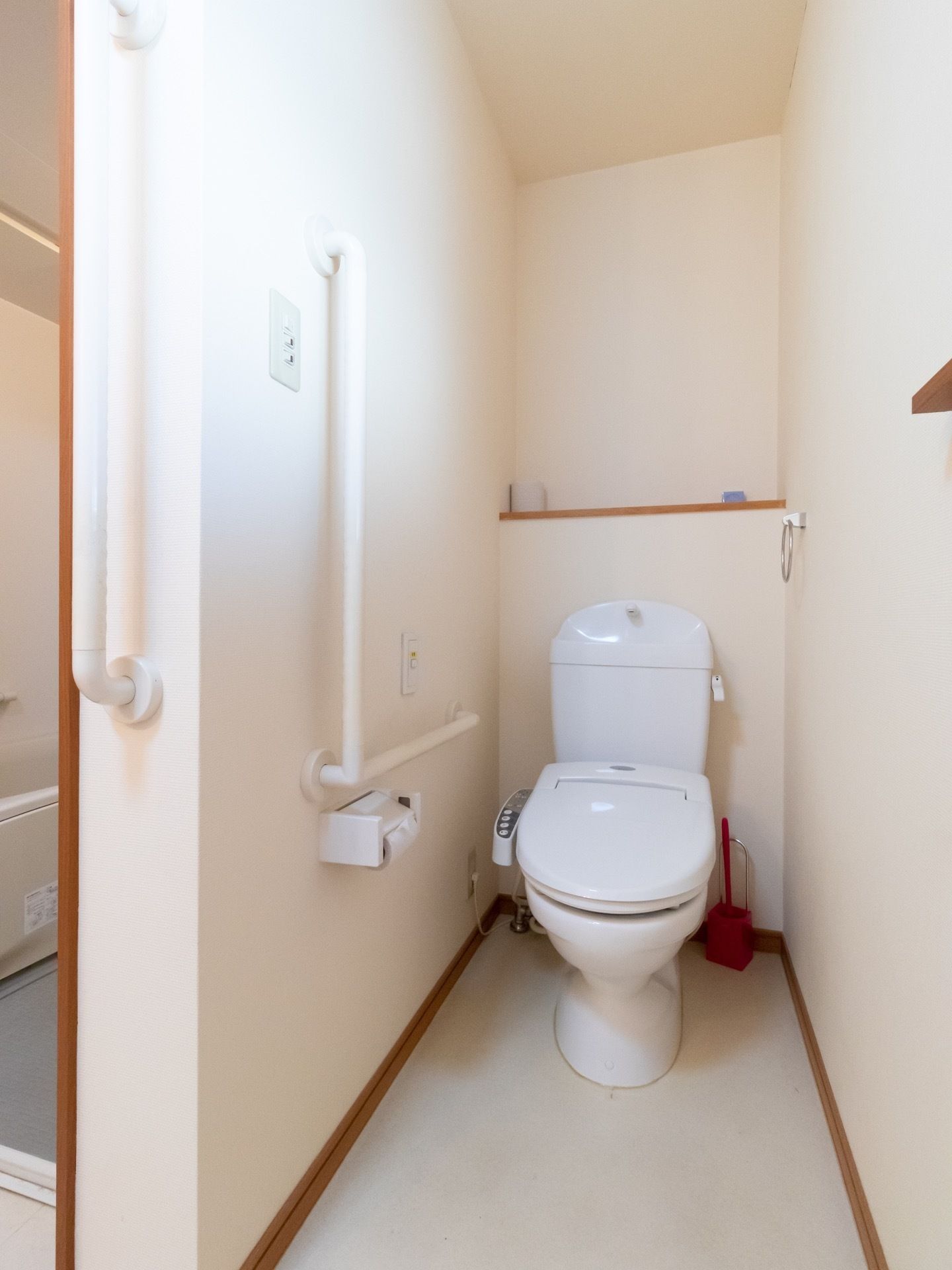 居室に備え付けられているトイレで、壁にはL字型の手すりやタオルハンガーが取り付けられている。温水洗浄機能付き便座が採用されている。