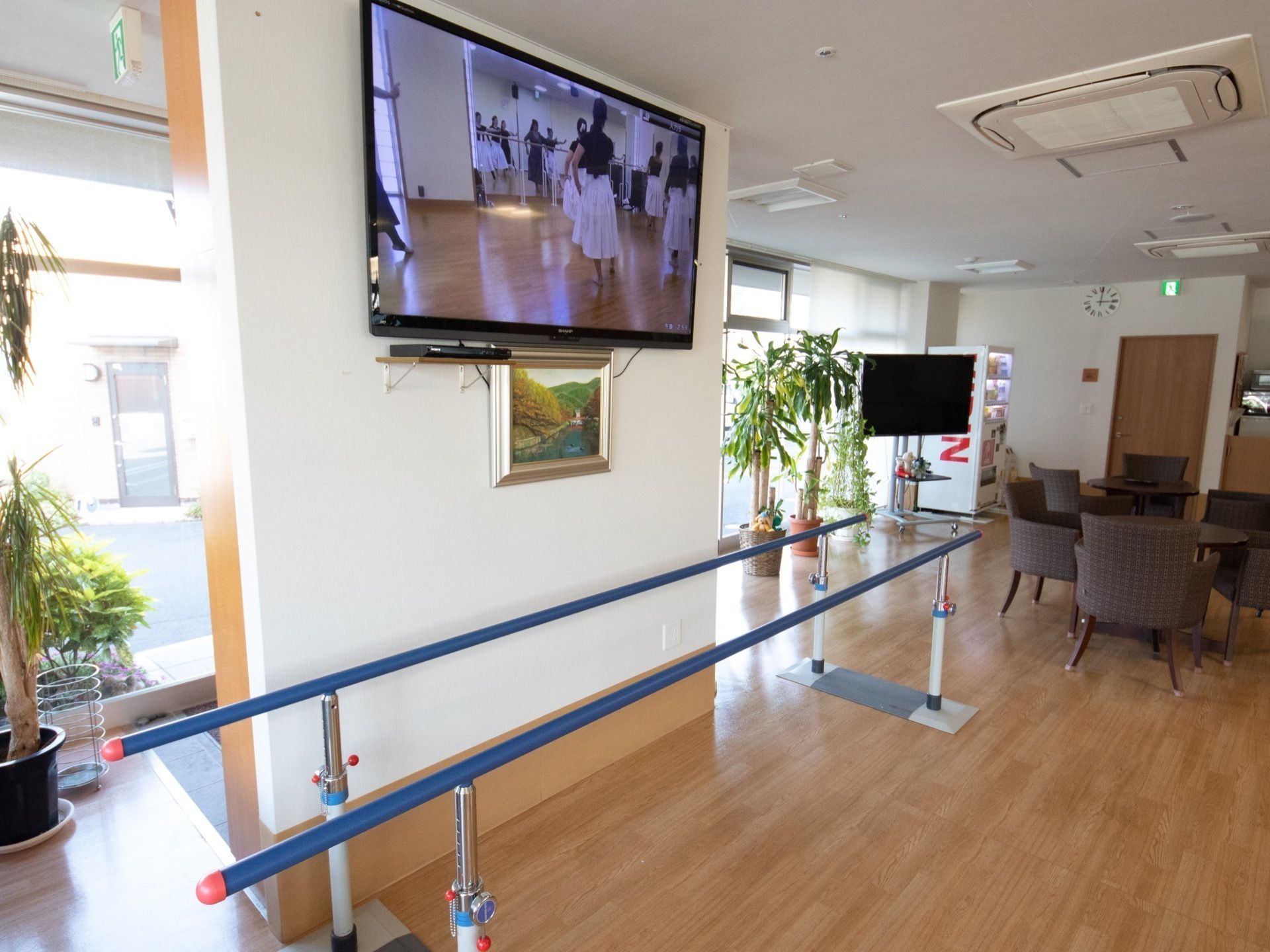 平行棒が明るく広々とした共有スペースに設置されている。体を支えながら歩行のリハビリなどをすることができる。