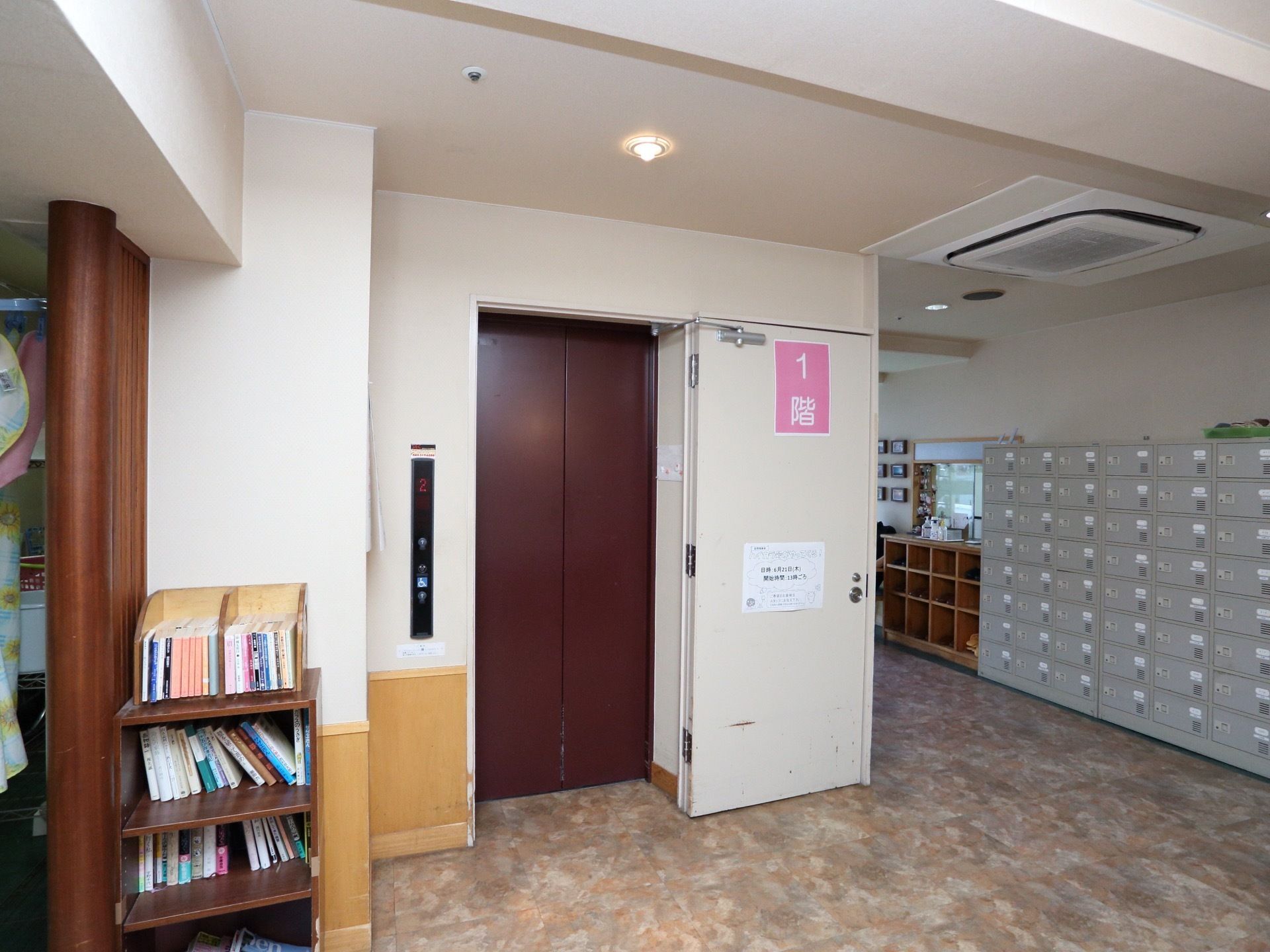 エレベーター横の壁に、大きく階が書かれた紙が貼られていてわかりやすい。操作盤に車椅子用ボタンがついている。手前に本棚が置かれている。