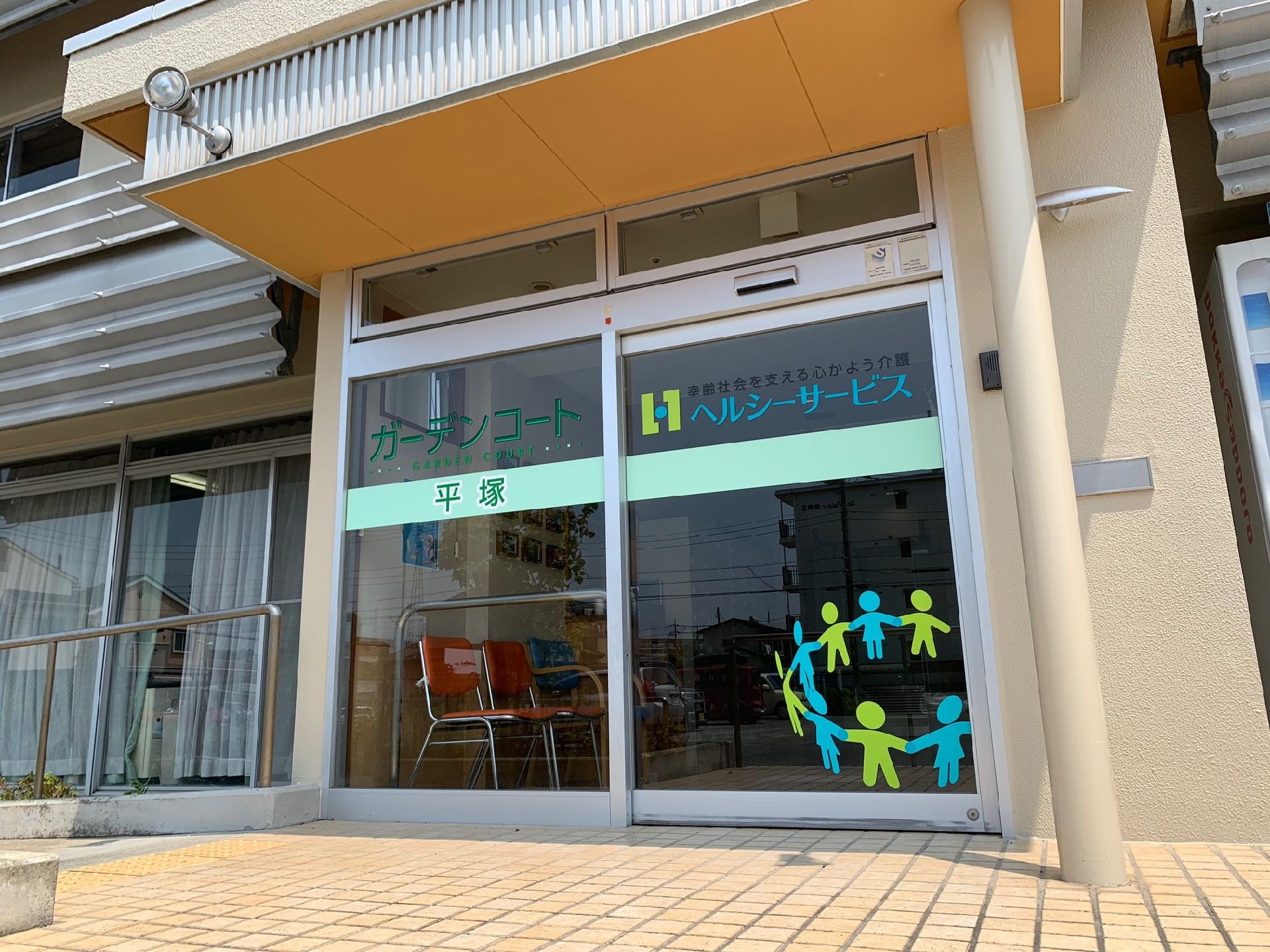 玄関には照明が2つ付いている。施設名がガラスのドアに書かれており、遠くからでもわかりやすい。ドアに描かれた絵がアットホームな印象を与える。