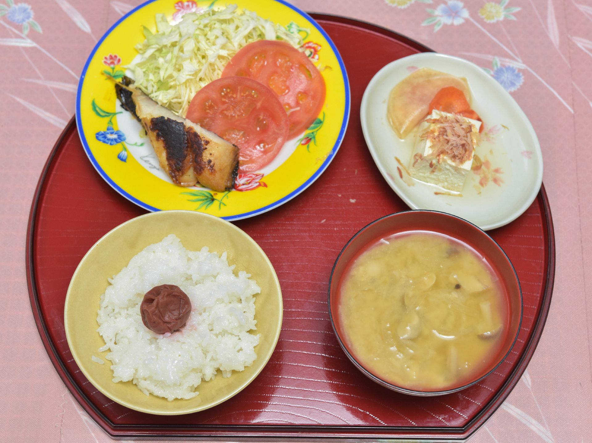お味噌汁と梅干しをのせたご飯、野菜サラダが添えられている。