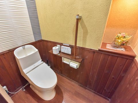 トイレ内の床はフローリングで、壁の下部分にも木材が使われている。右の角部分には棚があり、花籠の小物が置かれている。