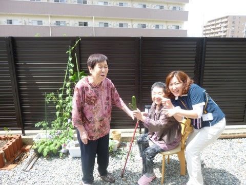 庭で笑顔の利用者とスタッフ