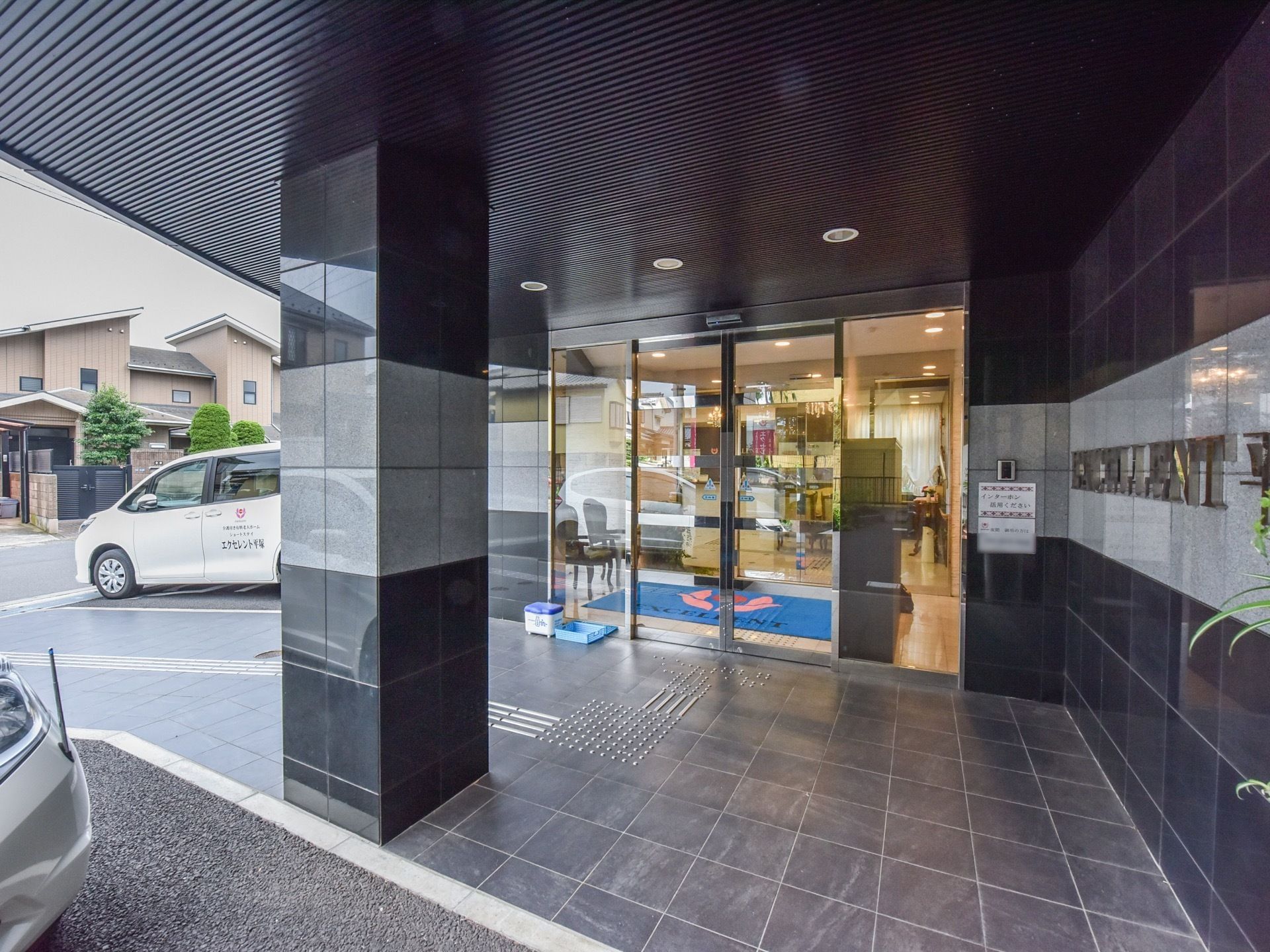 黒いタイルがすっきりとした印象を与える玄関。段差はなく点字ブロックもはっきりしているため安心感がある。