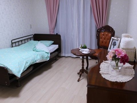 正面に窓があり、片側の壁際に低床型のベッドがある。反対側の壁にはテーブルと椅子があり、整理ダンスが並んでいる。