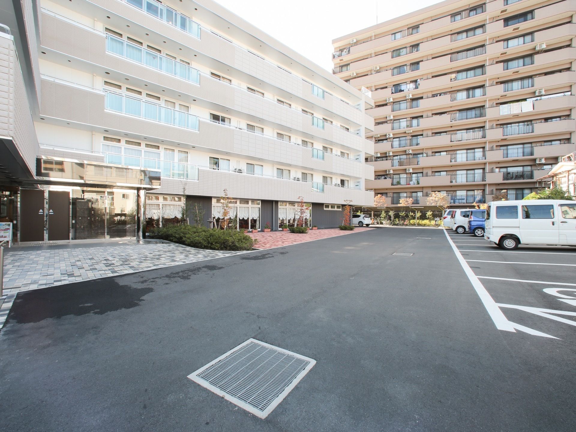 施設はマンションのような荘厳なたたずまいとなっており、その手前には広いスペースの道路と駐車場がある。
