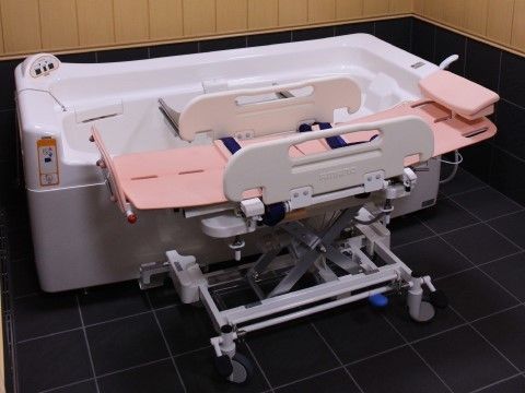 寝たままの状態で浴槽に移乗できる専用機械の様子。転倒防止の柵と安全ベルト、枕が備わっており、無理のない姿勢を保つことができる。