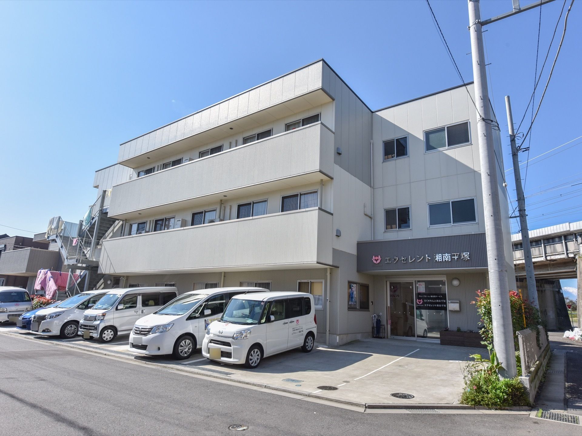 ３階建ての建物で、右の端が玄関になっている。２、３階の窓側には広いベランダがある。建物の正面は専用駐車場になっている。