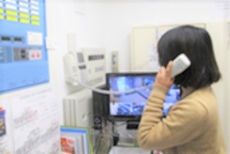 モニターが設置された部屋で電話を受けるスタッフ