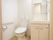 白で統一された、洋式のトイレと洗面化粧台。洗面化粧台の下には、収納もある。トイレのそばには、もちろん手すりが設置されている。