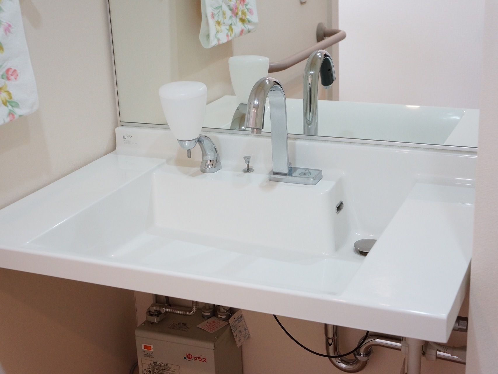 白色で長方形の洗面台である。ボタンを押すことで水を出したり止めたりすることができる。液体洗剤が備えられている。