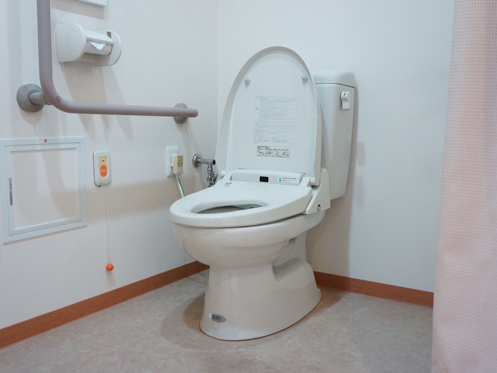 白色を基調とした個室内に洋式の便器が備わっている。壁にはL字型の手すりや緊急時呼び出しブザーが取り付けられている。