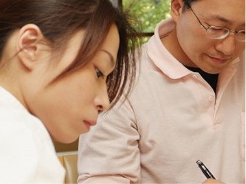 ある一室で男女のスタッフが机に向かい筆記をしている光景