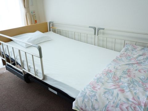 居室の介護用ベッドには、手すりを兼ねた柵が取り付けられている。また背もたれはリクライニングが可能となっている。