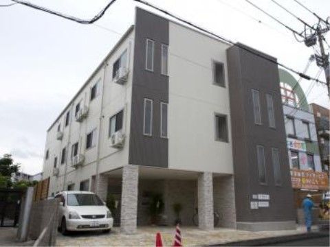 駐車スペースを備えた、モノトーンの外壁になっているモダンな施設外観