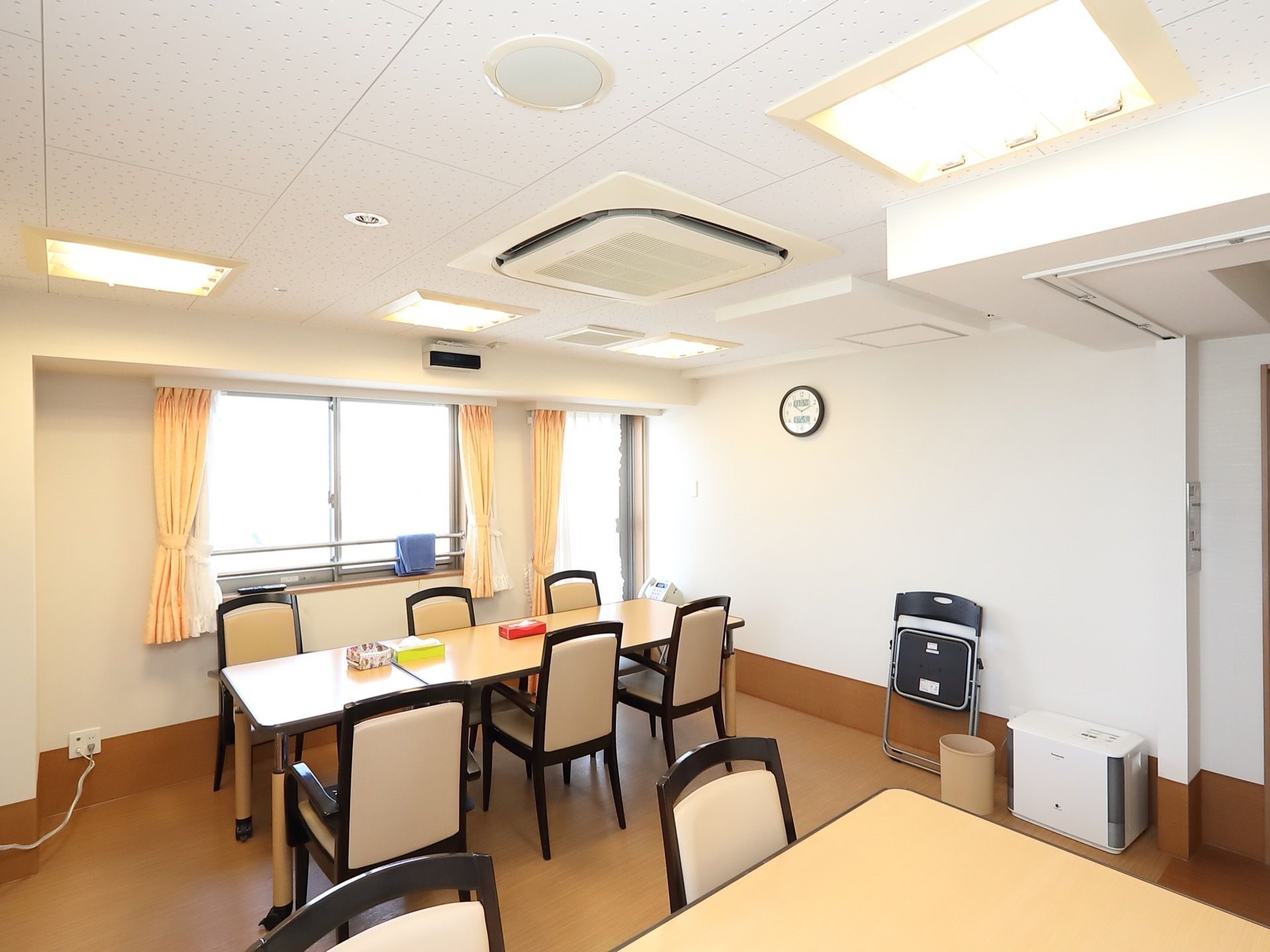 白を基調とした明るい食堂である。加湿器や６人掛けの広いダイニングテーブル、椅子、エアコンが完備されている。