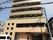 ８階建てのダークブラウンを基調とした近代的な建物である。エントランスの前には車が１台駐車するスペースがある。