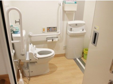 壁側にはＬ字の手すり、便器の脇には上下に稼働する手すりが設置されている。安心してご利用いただけるよう緊急用のボタンがある。