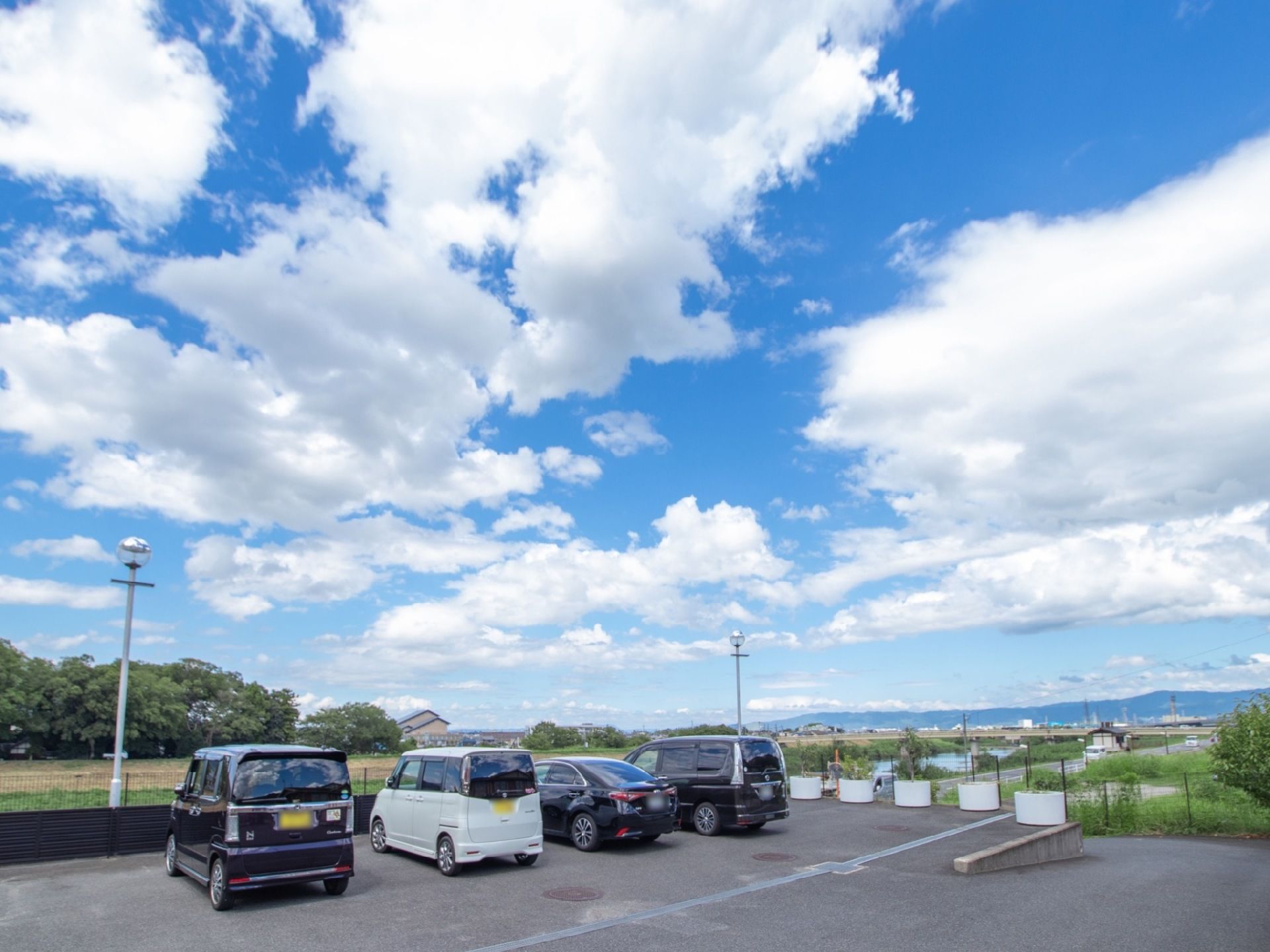 施設の敷地内には、広々とした駐車場が設けられている。周辺には川や畑など、のどかな風景が広がっている。