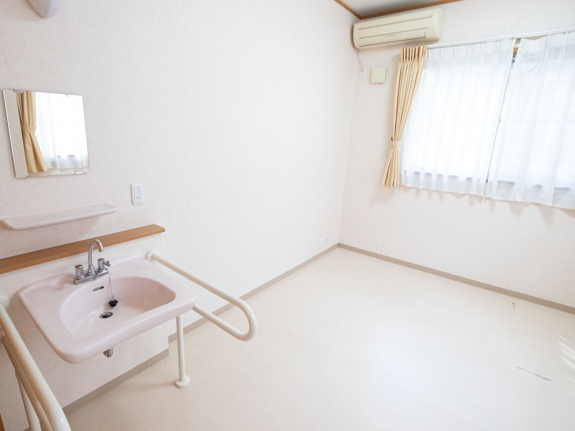 エアコンや洗面台が備わっている居室である。壁には、鏡や照明、コンセントが設置されている。外の景色を見ることが可能な窓がある。