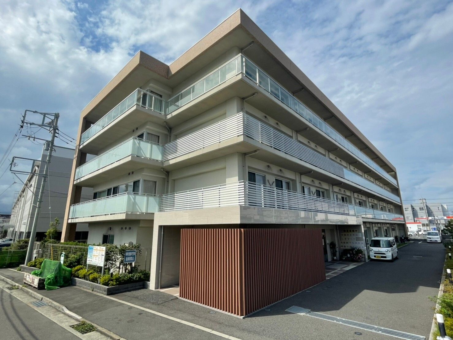 建物前に車が停められている4階建て高齢者施設の外観