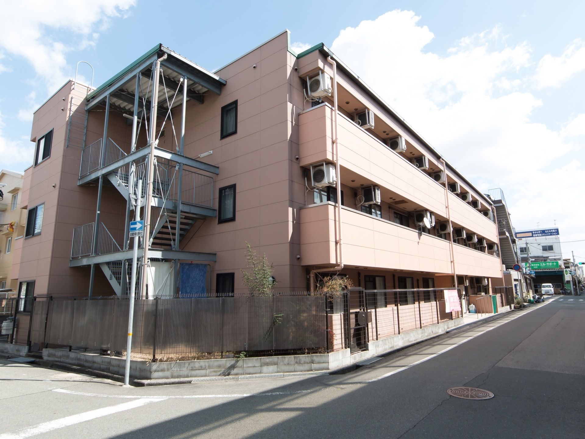 落ち着いたピンク色の3階建ての建物である。全ての居室からベランダへ出られて、窓には網戸が備わっている。