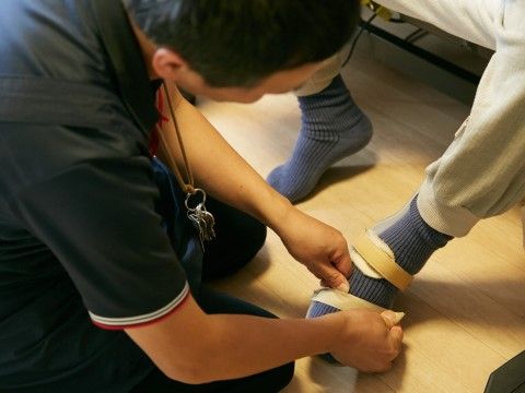 入居者様の左足のサポートを行っているスタッフの様子